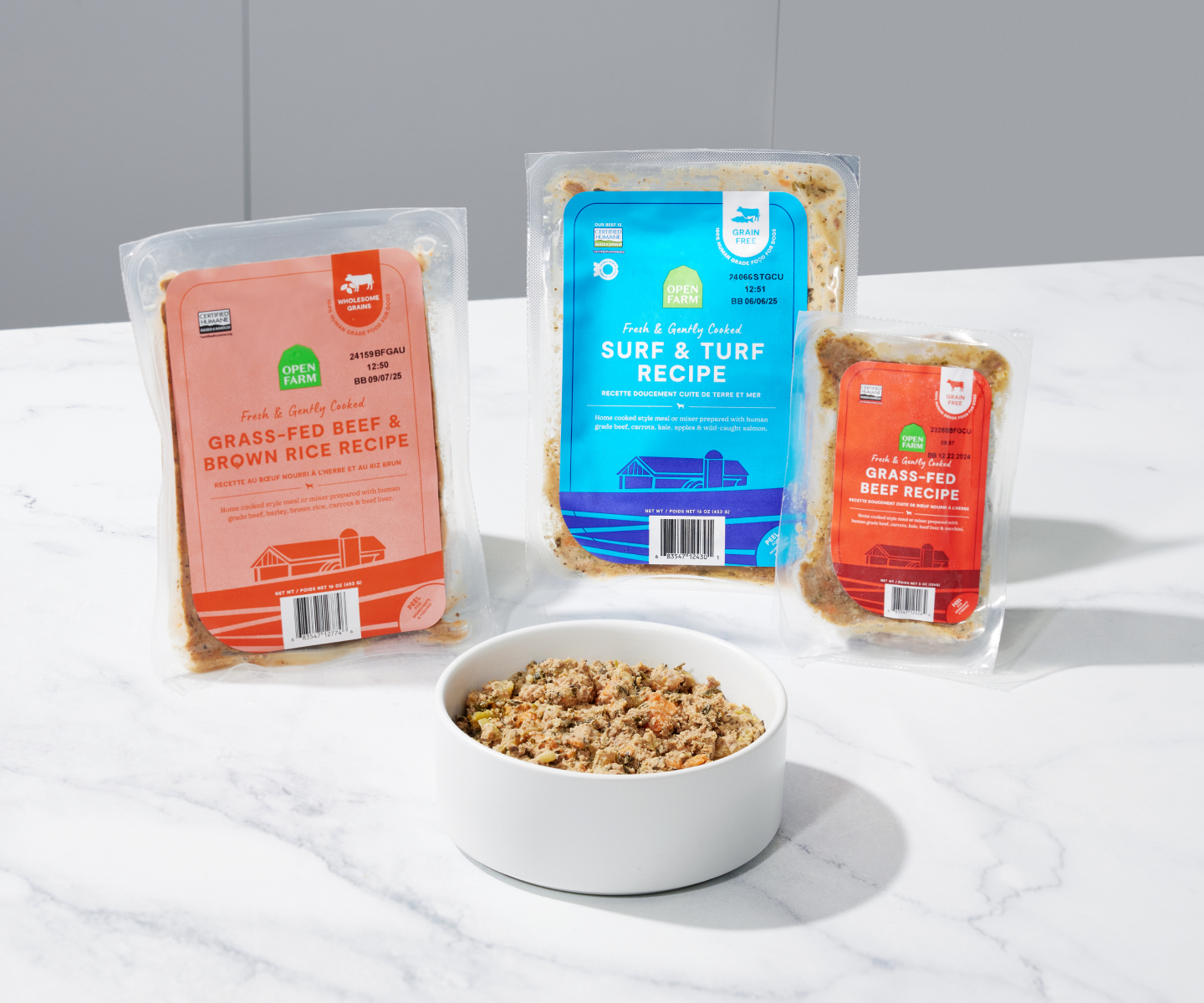 A bowl of gently cooked dog food surrounded by 3 packages of dog food 